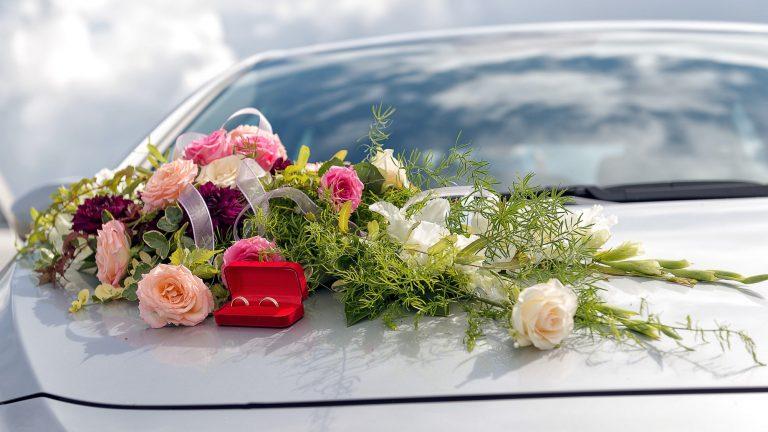 Flower decoration and a ring set on gray wedding car bonnet.